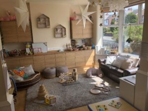 The front room has a large rug set out with natural wooden toys for babies to explore freely. There is a lovely home from home feel.